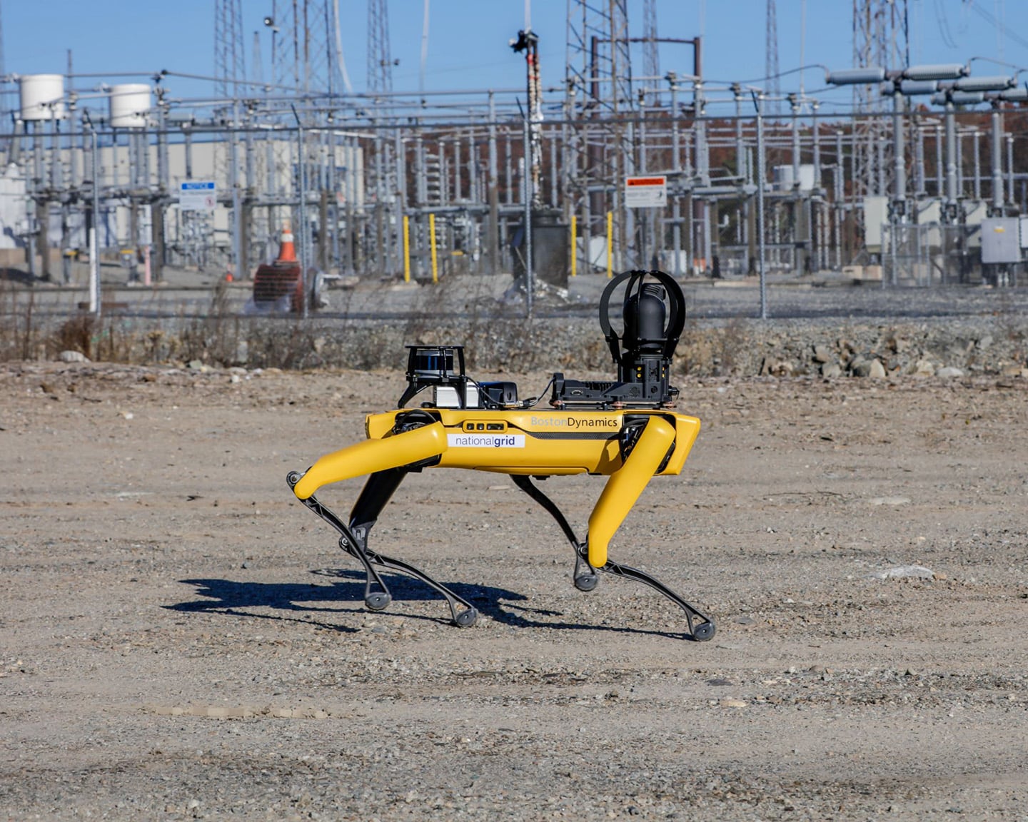 Spot walks over dirt at an electrical substation